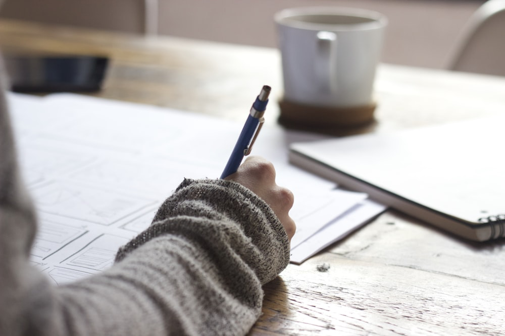 Adolescent qui écrit au stylo à son bureau